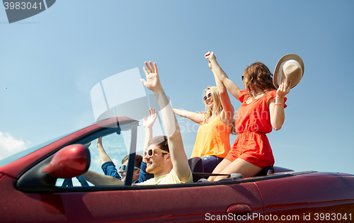 Image of happy friends driving in cabriolet car at country