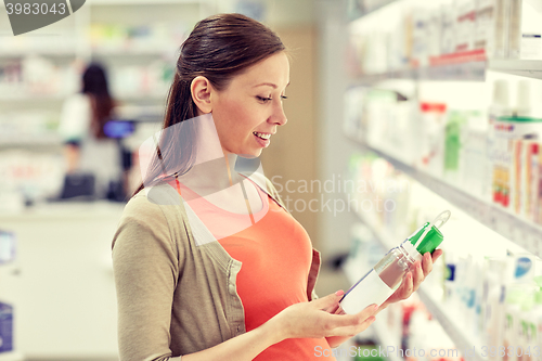 Image of happy pregnant woman choosing lotion at pharmacy