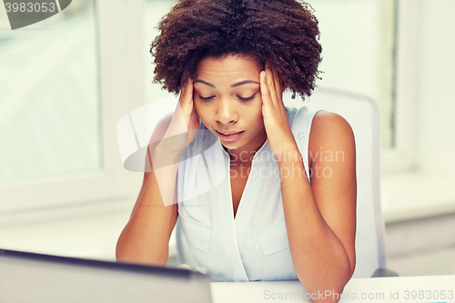 Image of african woman with laptop at office