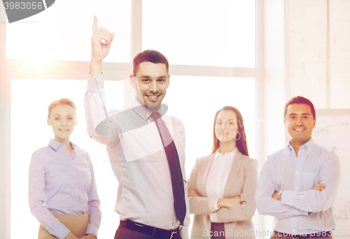 Image of smiling businessman in office with team on back