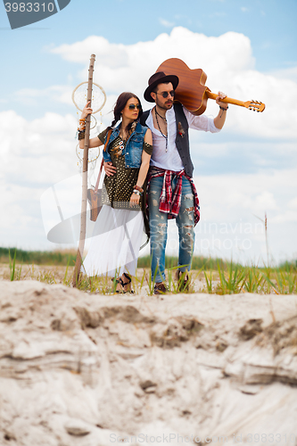 Image of Man and woman as boho hipsters against blue sky