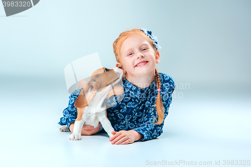 Image of The happy girl and a beagle puppie on gray background