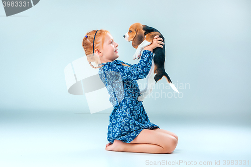 Image of The happy girl and a beagle puppie on gray background