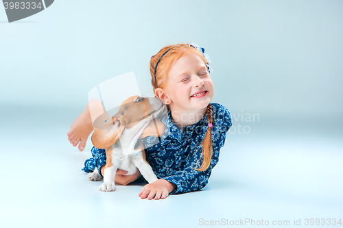 Image of The happy girl and a beagle puppie on gray background