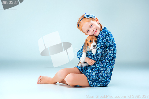 Image of The happy girl and a beagle puppie on gray background