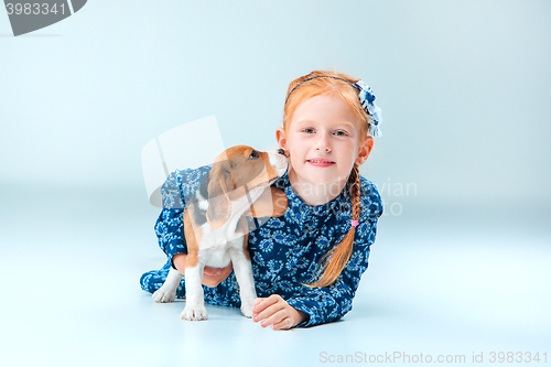 Image of The happy girl and a beagle puppie on gray background