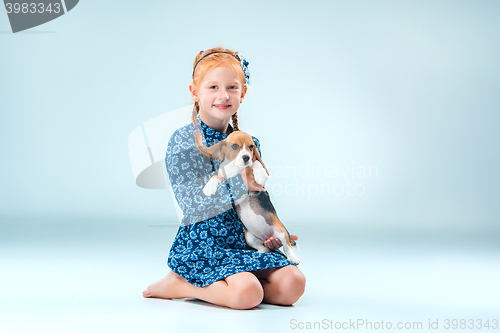 Image of The happy girl and a beagle puppie on gray background