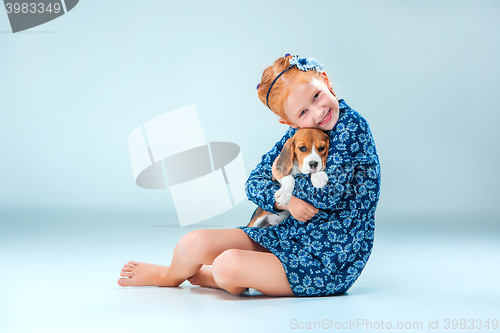 Image of The happy girl and a beagle puppie on gray background