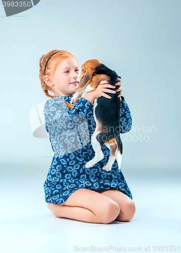 Image of The happy girl and a beagle puppie on gray background