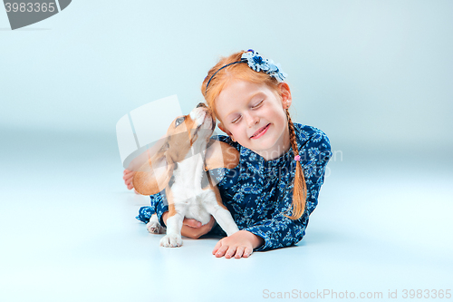 Image of The happy girl and a beagle puppie on gray background