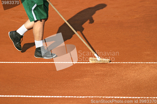 Image of Worker cleans a line of tennis court