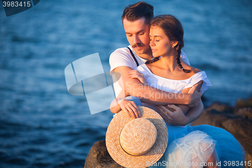 Image of Happy young romantic couple relaxing on the beach watching the sunset