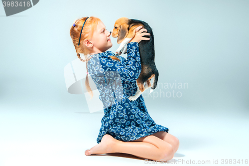 Image of The happy girl and a beagle puppie on gray background