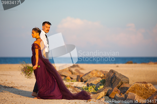 Image of Young romantic couple relaxing on the beach watching the sunset