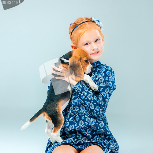 Image of The happy girl and a beagle puppie on gray background