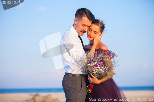 Image of Young romantic couple relaxing on the beach watching the sunset
