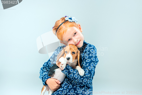 Image of The happy girl and a beagle puppie on gray background