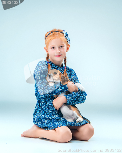 Image of The happy girl and a beagle puppie on gray background