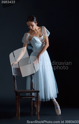 Image of Portrait of the classical ballerina in white dress on black background