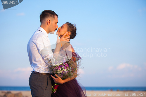 Image of Young romantic couple relaxing on the beach watching the sunset