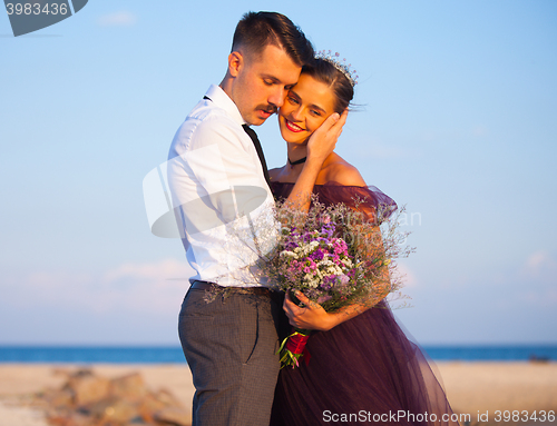 Image of Young romantic couple relaxing on the beach watching the sunset