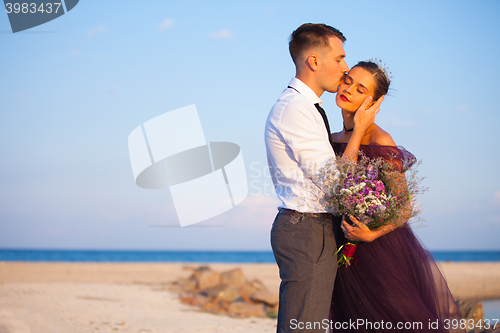 Image of Young romantic couple relaxing on the beach watching the sunset