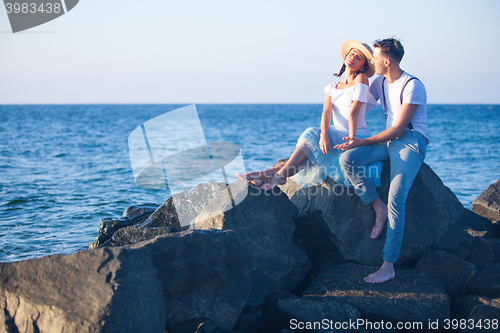 Image of Happy young romantic couple relaxing on the beach watching the sunset