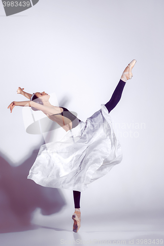 Image of Ballerina in black outfit posing on toes, studio background.