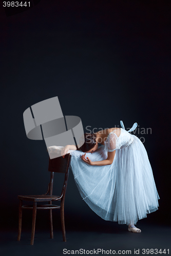 Image of Portrait of the classical ballerina in white dress on black background