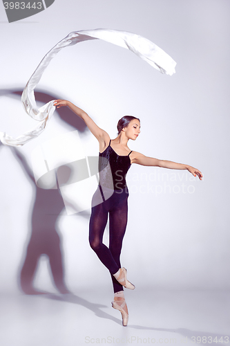 Image of Ballerina in black outfit posing on toes, studio background.