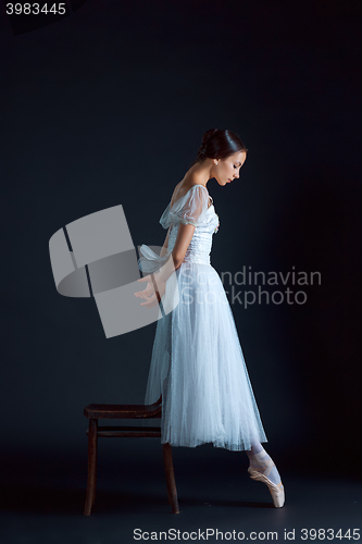 Image of Portrait of the classical ballerina in white dress on black background