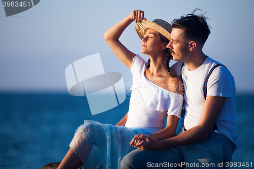 Image of Happy young romantic couple relaxing on the beach watching the sunset