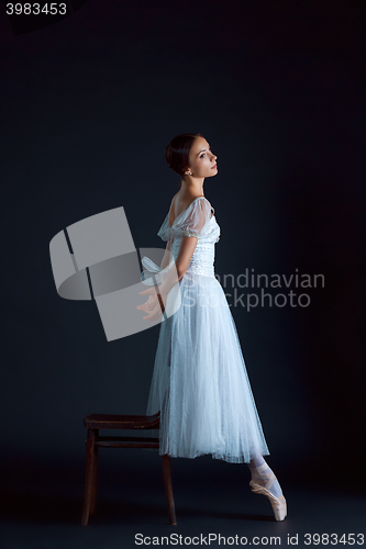 Image of Portrait of the classical ballerina in white dress on black background