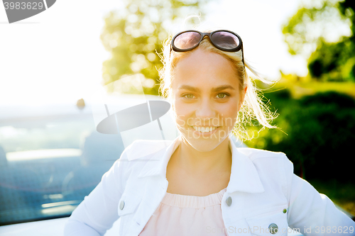 Image of happy teenage girl or young woman near car