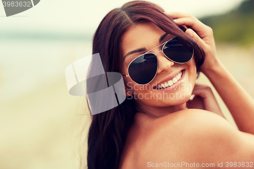 Image of smiling young woman with sunglasses on beach