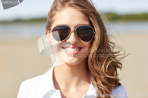 Image of smiling young woman in sunglasses on beach