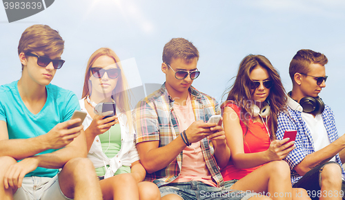 Image of group of friends with smartphones outdoors