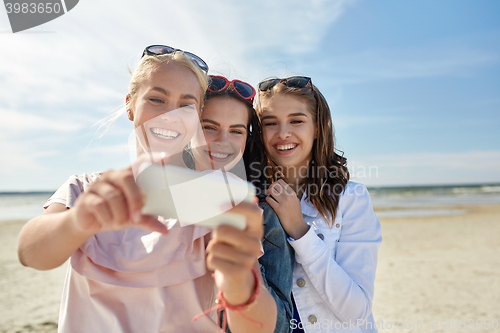 Image of group of smiling women taking selfie on beach