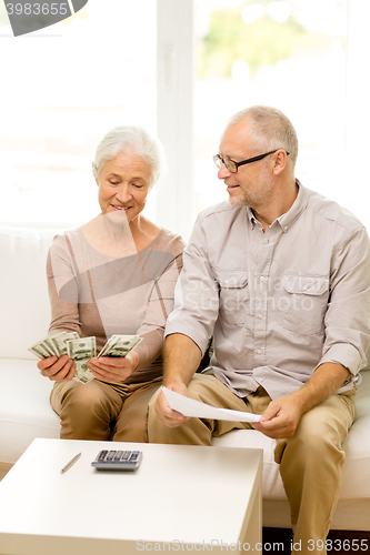 Image of senior couple with money and calculator at home