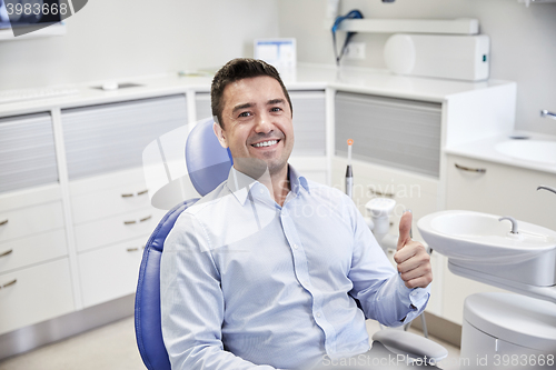 Image of happy man showing thumbs up at dental clinic