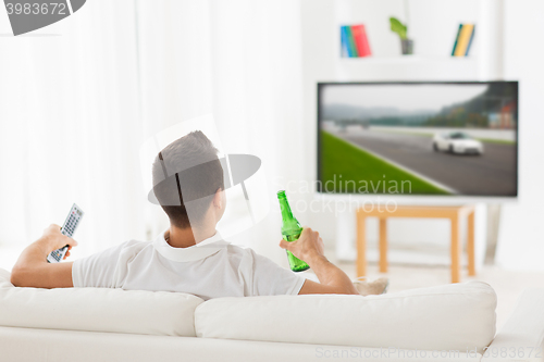 Image of man watching tv and drinking beer at home