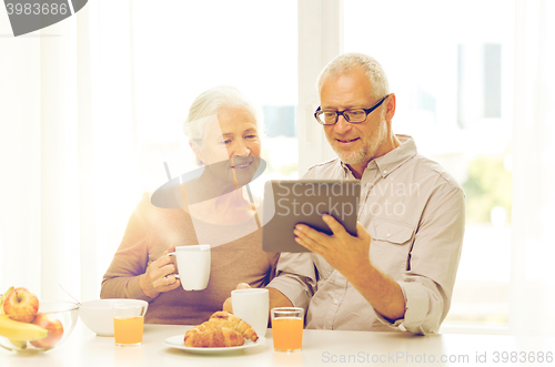 Image of happy senior couple with tablet pc at home