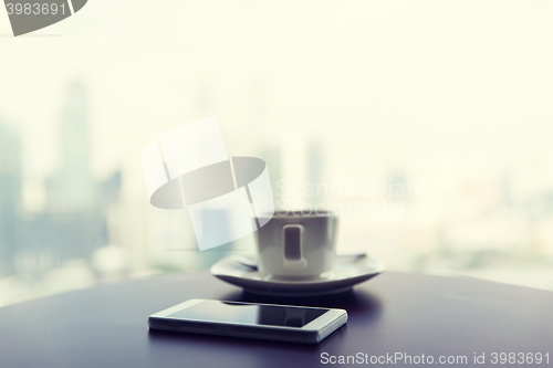 Image of close up of smartphone and coffee cup on table