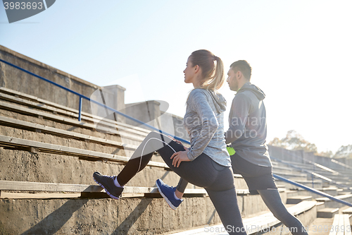 Image of couple stretching leg on stands of stadium