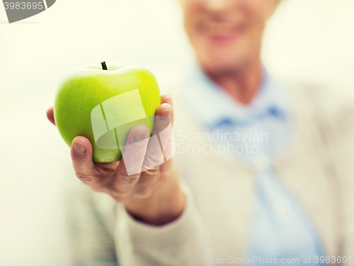 Image of close up of senior woman hand holding green apple