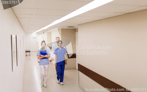 Image of group of medics or doctors walking along hospital