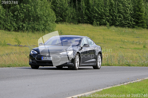 Image of Black Tesla Model S Electric Car on Green Rural Road