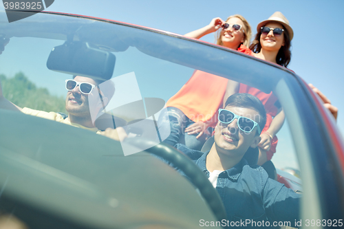 Image of happy friends driving in cabriolet car