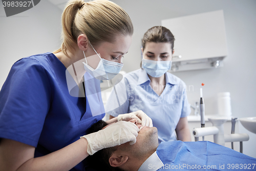 Image of female dentist checking patient dental occlusion