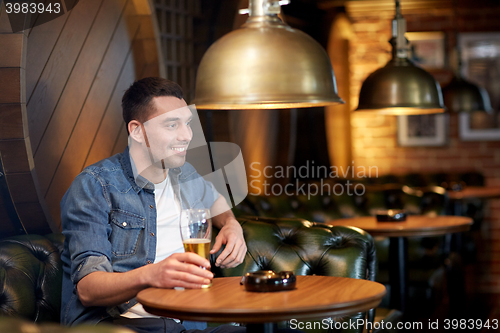 Image of happy man drinking draft beer at bar or pub